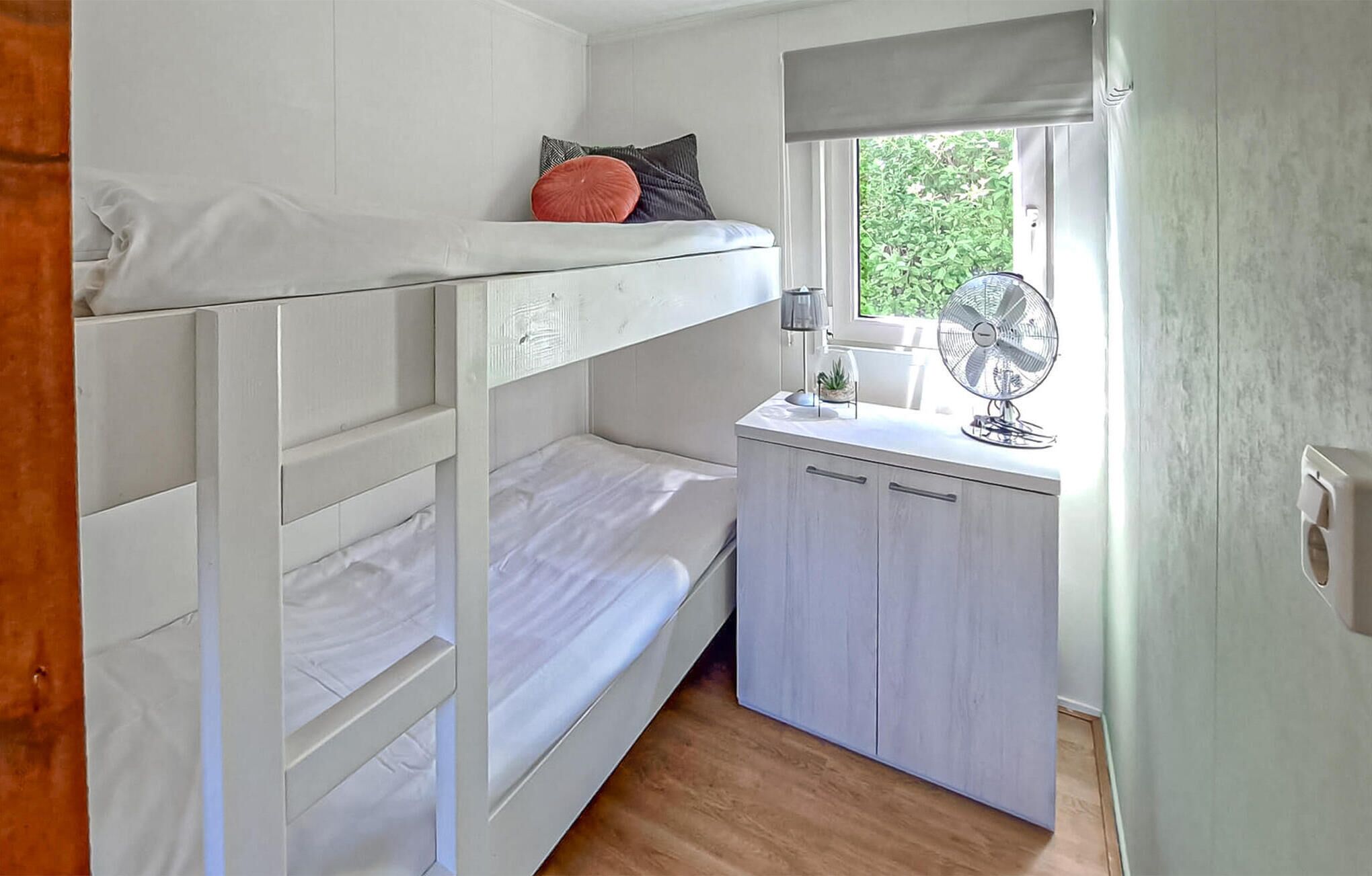 Een slaapkamer met een stapelbed, bureau en raam.