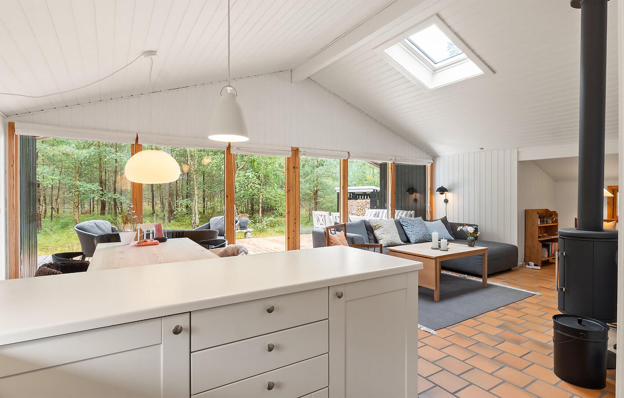 Eine moderne Küche mit einer großen Kochinsel, einem Essbereich mit Tisch und Stühlen sowie einer gemütlichen Sitzecke mit Sofa und Kissen.