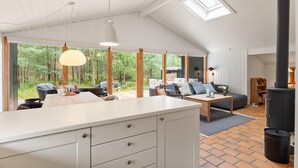Eine moderne Küche mit einer großen Kochinsel, einem Essbereich mit Tisch und Stühlen sowie einer gemütlichen Sitzecke mit Sofa und Kissen.