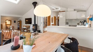 Eine moderne Küche mit weißen Schränken, einer zentralen Kochinsel und einem Essbereich mit einem Holztisch und Stühlen.