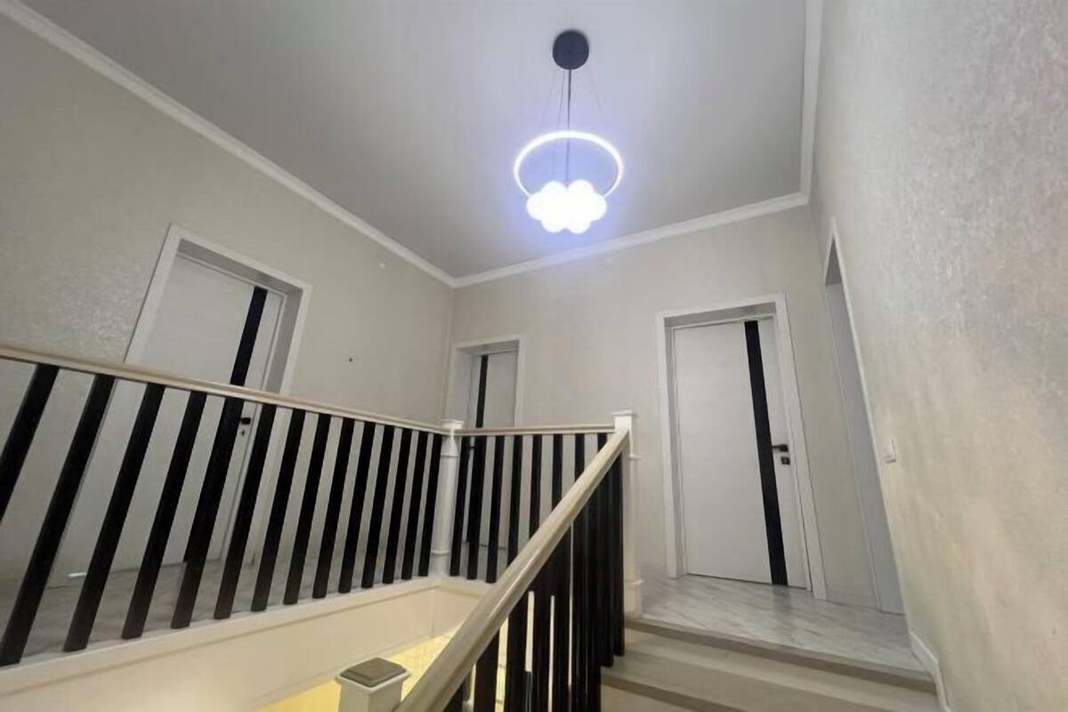 A staircase with a white railing and black balusters, leading to a landing with a door.