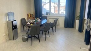 A dining area with a round table, chairs, a water dispenser, and a radiator. - HOMESTAY (Almaty)