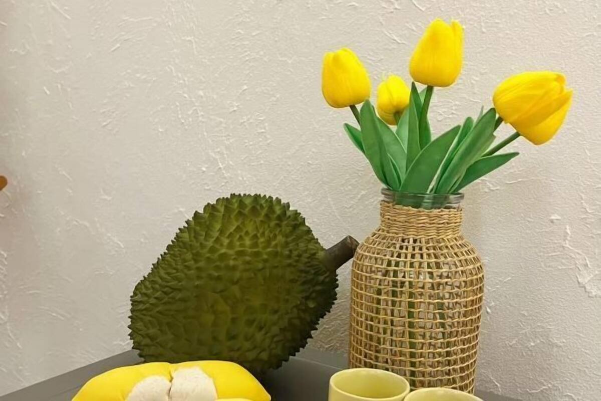 A vase with yellow flowers, a textured green object, and a yellow object on a table.