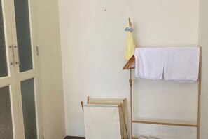 A room with a wooden drying rack, a white towel hanging on a hook, and a door with glass panels. - Durian Family Hotel (Bangkok)