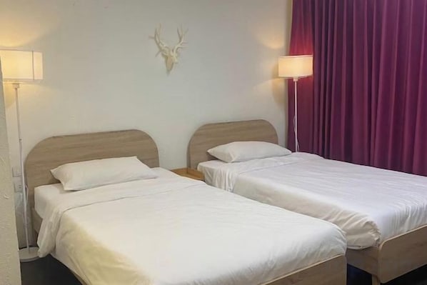 Two single beds with wooden headboards, white bedding, and a wall-mounted deer head decoration.