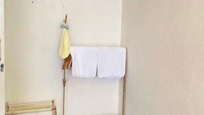Ein Zimmer mit einem Wäscheständer aus Holz, der weiße Handtücher und ein gelbes Tuch trägt.