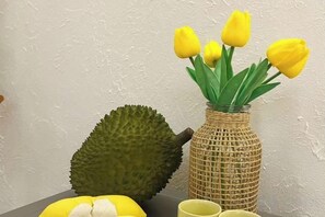 A vase with yellow flowers and a large fruit. - Durian Family Hotel (Bangkok)