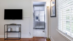 A modern kitchen with a built-in refrigerator, a flat-screen TV mounted on the wall, and a bookshelf. - Heart of Midtown - Newly Renovated - Atlanta Home (Atlanta)