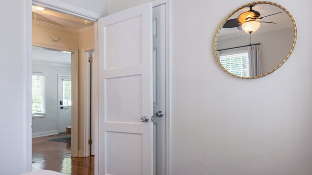 A hallway with a white door, a round mirror on the wall, and a ceiling fan. - Heart of Midtown - Newly Renovated - Atlanta Home (Atlanta)