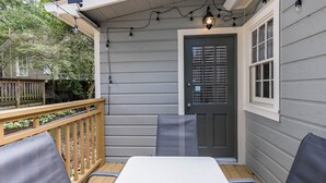 A covered outdoor seating area with a table and chairs, a wooden deck, and string lights. - Heart of Midtown - Newly Renovated - Atlanta Home (Atlanta)