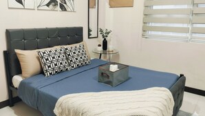 Een slaapkamer met een bed, nachtkastje, raam met zonwering en wanddecoratie.