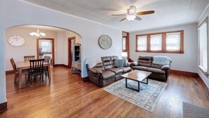 A spacious living room with a wooden dining table, two leather sofas, and a ceiling fan. - The Charming Chestnut (Arkansas City)