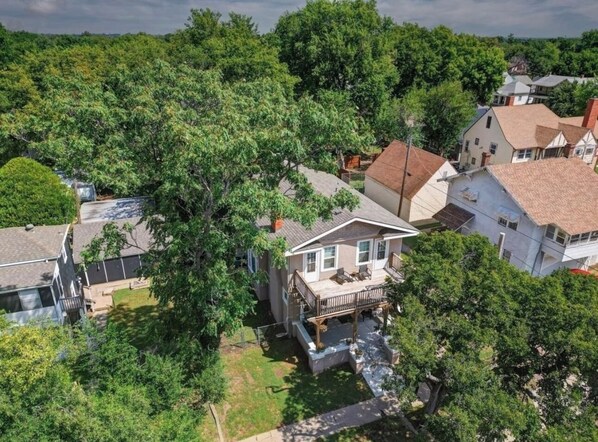 An aerial view of a residential area with houses, a large tree, and a small stream. - The Charming Chestnut (Arkansas City)