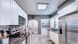 A modern kitchen with white cabinets, stainless steel appliances, and a marble countertop. - The Charming Chestnut (Arkansas City)
