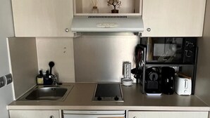 A compact kitchen with a clock, a sink, a toaster, and a microwave. - French Riviera getaway -Studio at Château des Artistes (Le Cannet)