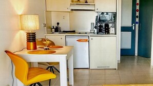 A compact hotel room with a dining area, kitchenette, and a bed with a yellow bedspread. - French Riviera getaway -Studio at Château des Artistes (Le Cannet)