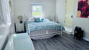 A bedroom with a bed, bedside tables, a window, a door, and a painting on the wall. - Amazing 2-bedroom house in Astoria (Astoria)
