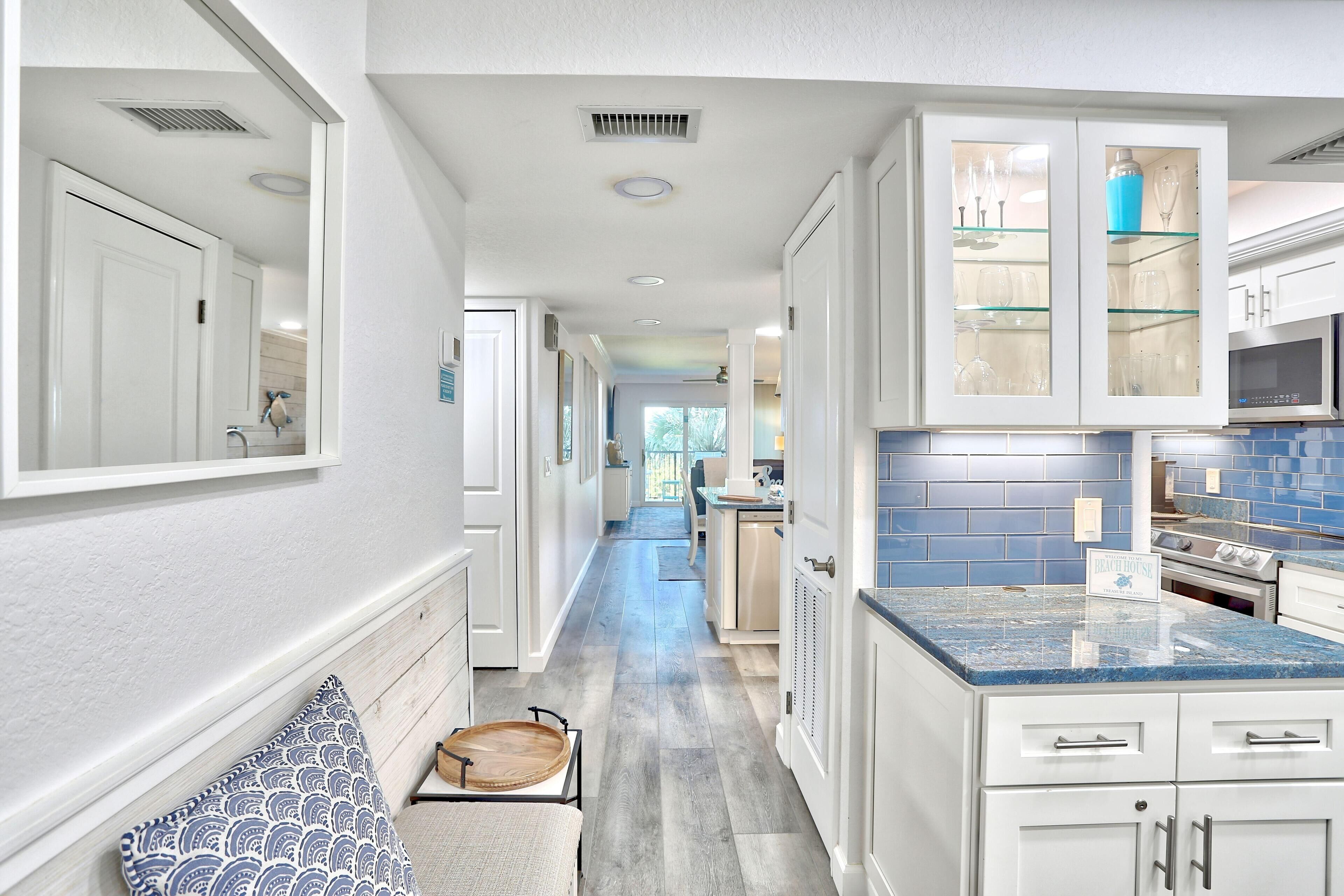 A modern kitchen with white cabinetry, a blue-tiled backsplash, and a built-in microwave.