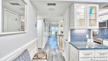 A modern kitchen with white cabinetry, a blue-tiled backsplash, and a built-in microwave.