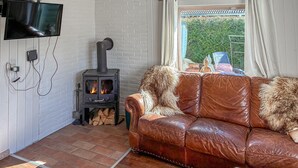 A cozy living room with a leather sofa, a fireplace, and a TV mounted on the wall.