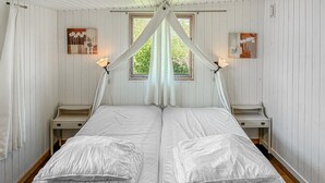 A bed with a canopy, two bedside tables, and artwork on the walls.
