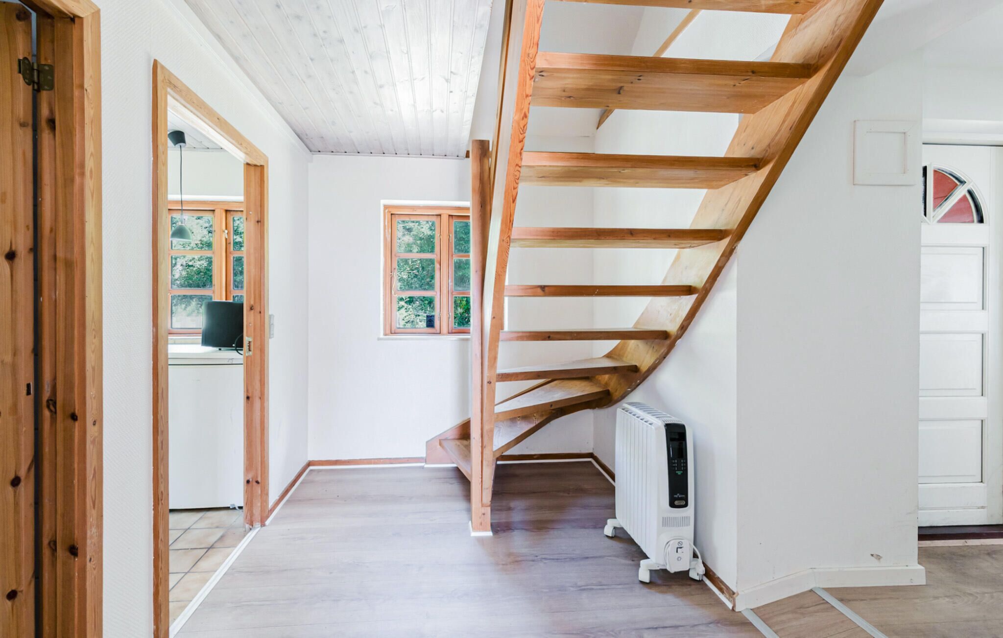 Ein geräumiger Raum mit einer Holztreppe, einem Heizkörper und einer Tür mit Fenster.