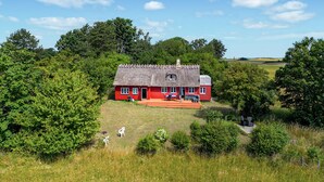 A red house with a thatched roof surrounded by greenery. - Gorgeous home in Karrebæksminde with WiFi (Karrebæksminde)