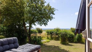 A patio with a cushioned seating area, a wooden deck, and a view of the landscape and distant horizon. - Gorgeous home in Karrebæksminde with WiFi (Karrebæksminde)