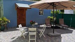 Eine Terrasse mit Tisch und Stühlen, eine Holztür und ein großer Sonnenschirm.