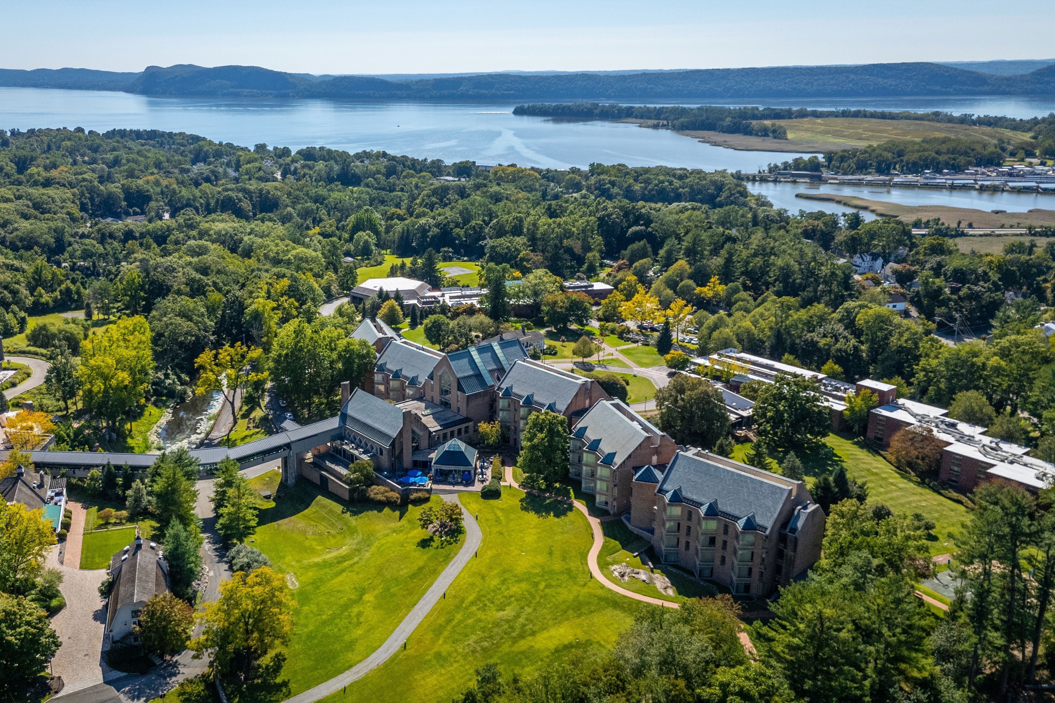 Vista aérea de un campus con varios edificios, un patio central y un lago al fondo.