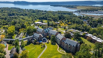 An aerial view of a campus with multiple buildings, a central courtyard, and a lake in the background.