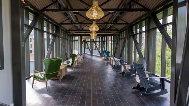 Un espace abrité équipé de matériel d’exercice, de chaises et offrant une vue grâce à de grandes fenêtres.