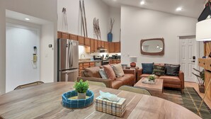 Eine moderne Küche mit Edelstahlgeräten, ein Essbereich mit Holztisch und ein Wohnzimmer mit Ledersofas und Couchtisch.