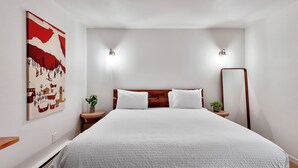 Ein Schlafzimmer mit einem großen Bett, zwei Nachttischen mit Lampen, einem Wandspiegel und einem Bild an der Wand.