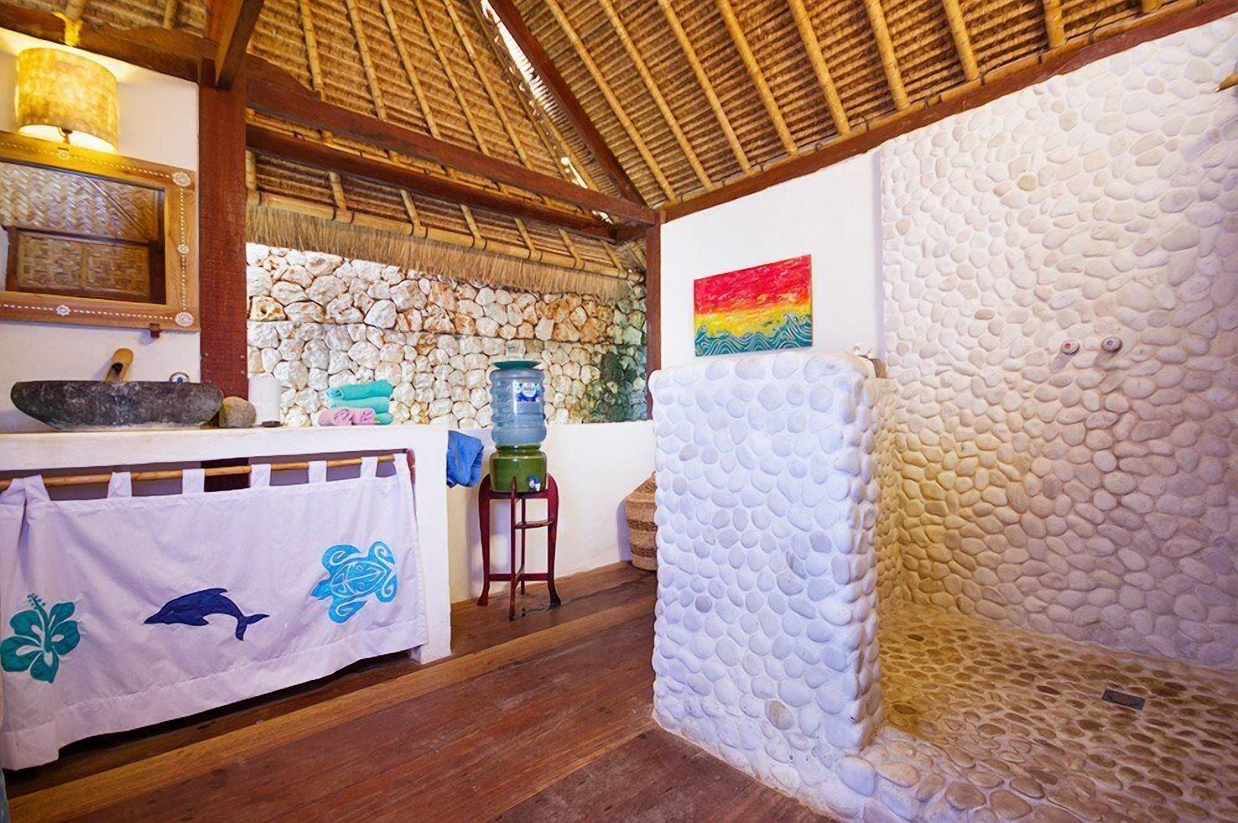 Una habitación con pared de piedra, techo de madera, una mesa con una toalla y un dispensador de agua.