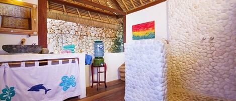 A room with a stone wall, a wooden ceiling, a table with a towel, and a water dispenser.