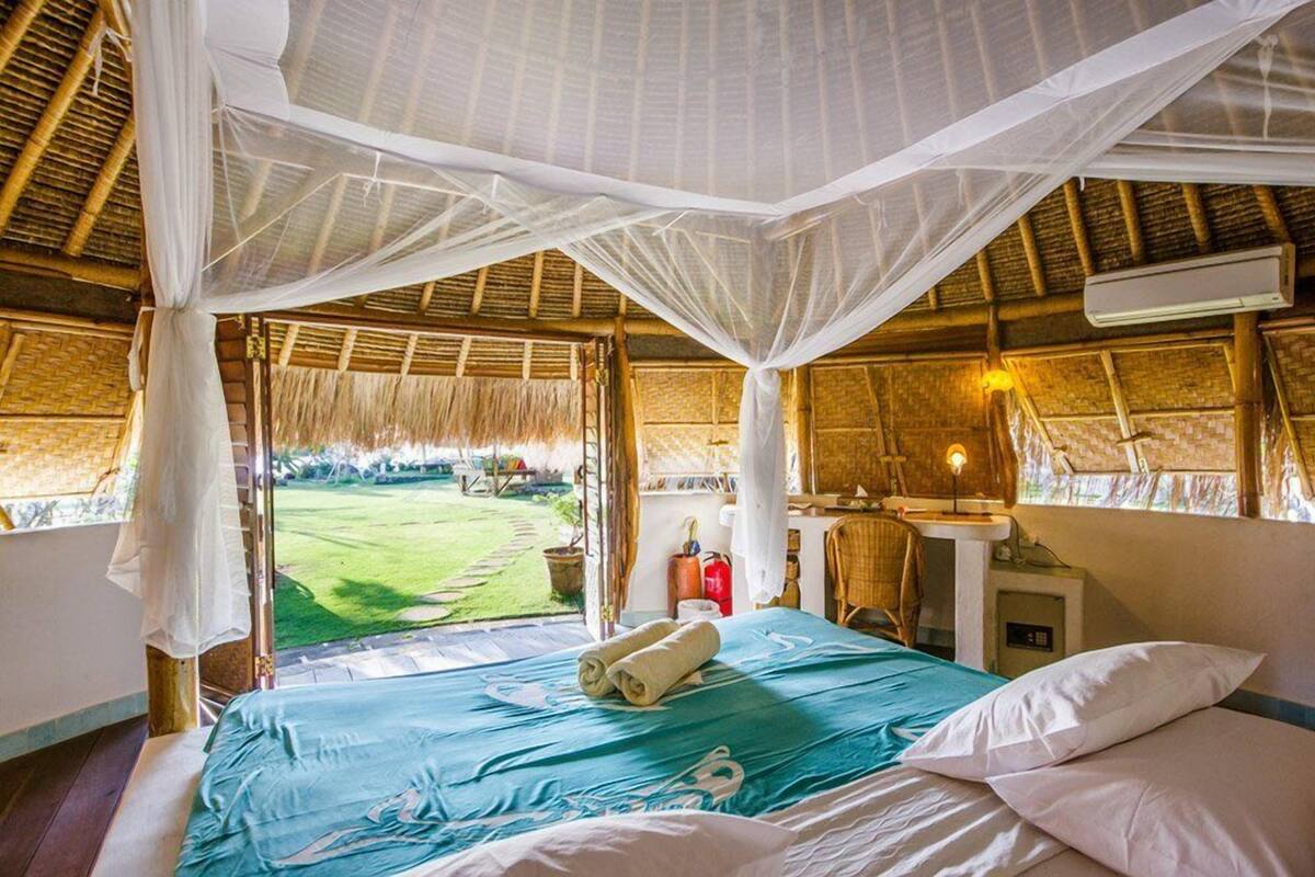 Een kamer met een bed, een wastafel en uitzicht op een groen veld.
