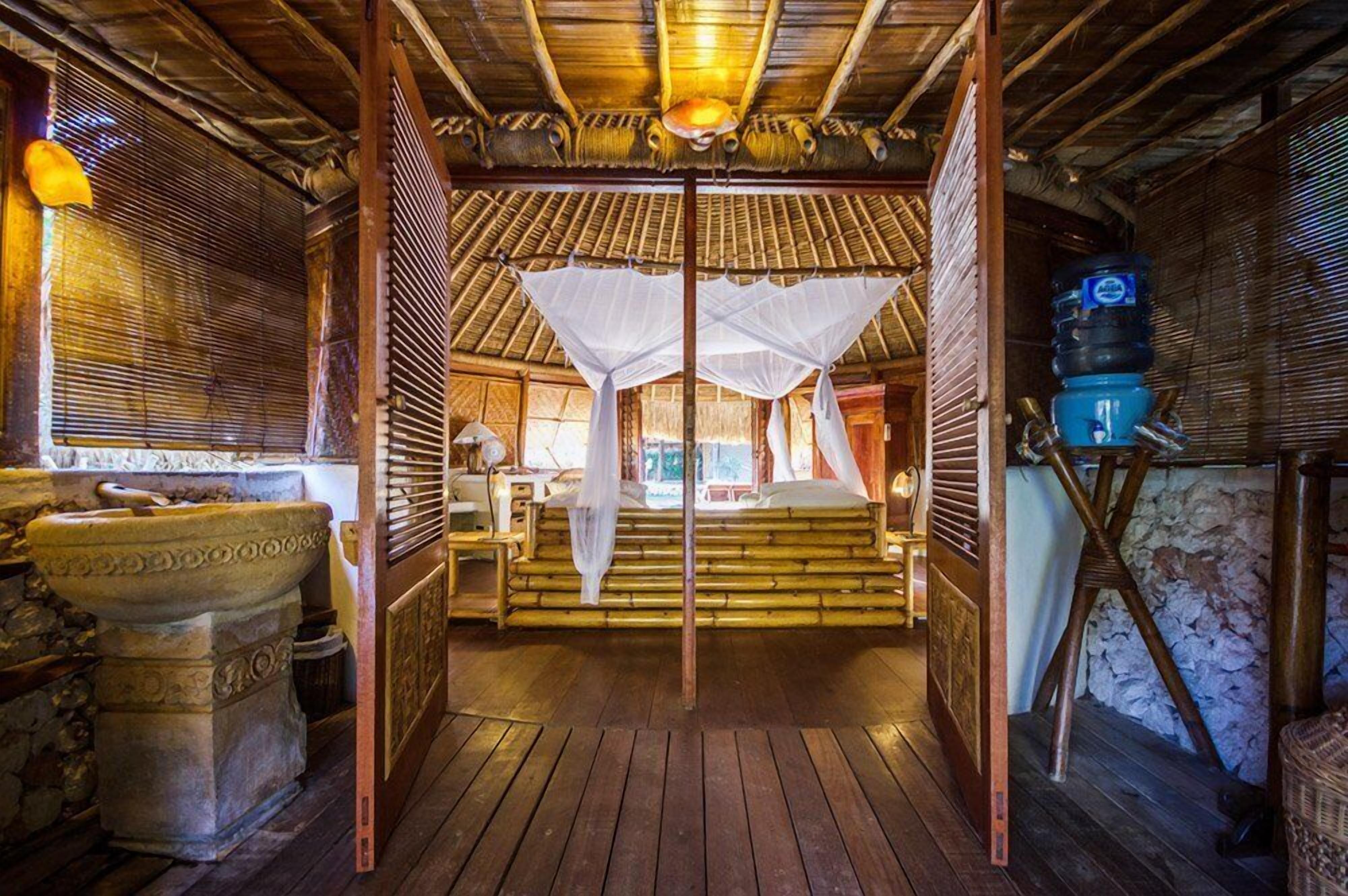 Une chambre traditionnelle équipée d’un lit, d’une moustiquaire et d’un distributeur d’eau.