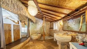 Un bagno con pareti in pietra, un lavandino grande e uno spazio doccia.