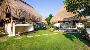 Un complexe hôtelier tropical doté de bungalows aux toits de chaume, d’une piscine et d’une pelouse bien entretenue.