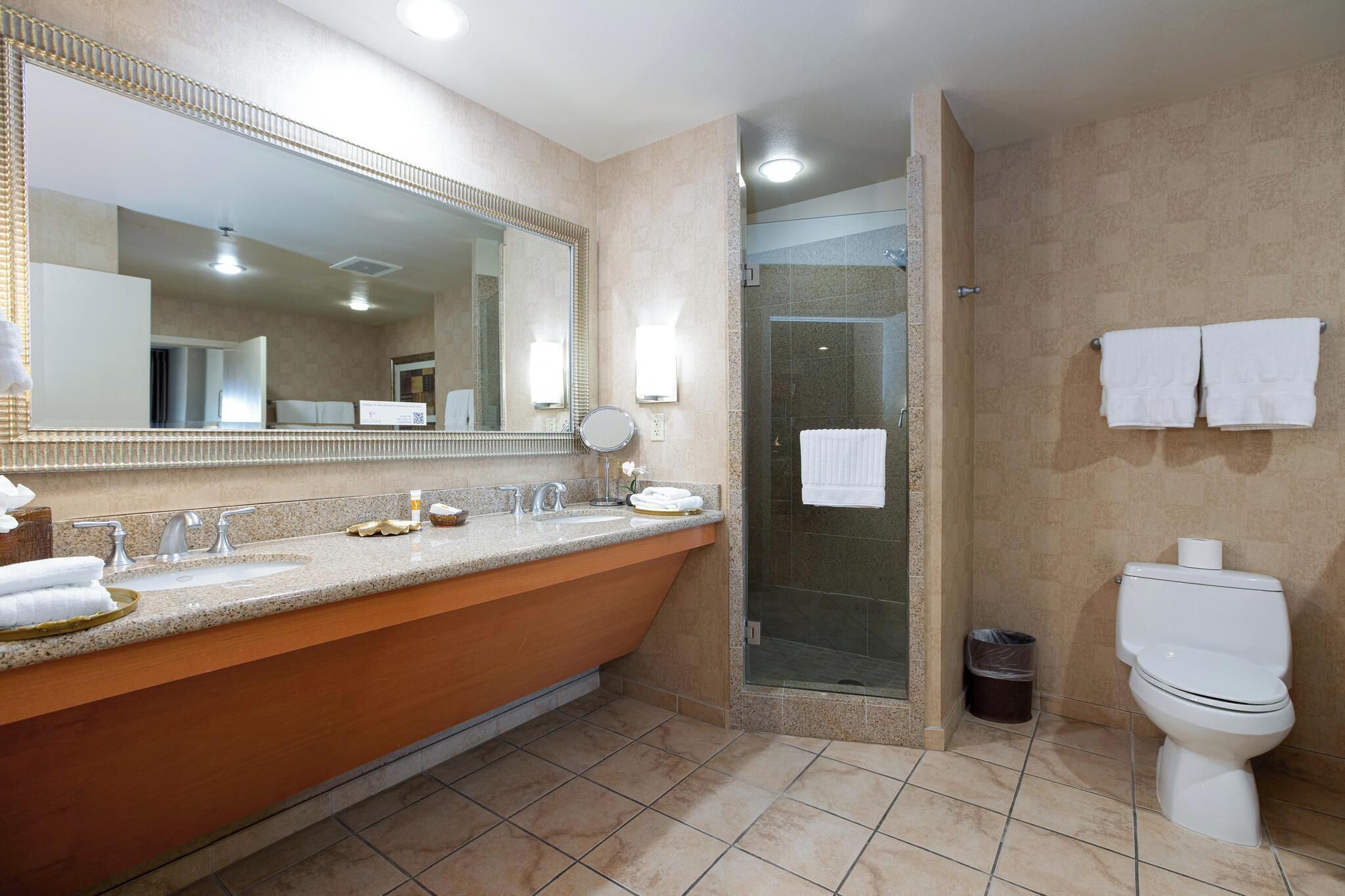 Een moderne badkamer met een grote spiegel, een wastafel met opbergruimte, een douchecabine en een toilet.