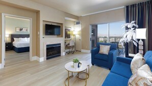 Une chambre d’hôtel moderne comprenant un espace de vie, une chambre à coucher, une cheminée, une télévision et un balcon avec vue.