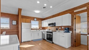 Una cocina compacta con gabinetes blancos, un microondas, una estufa y un refrigerador.