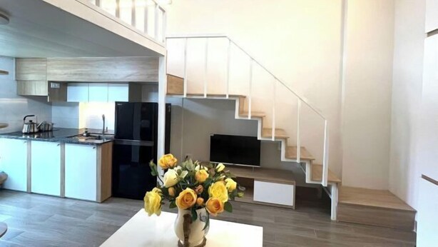Eine moderne Küche mit eingebautem Herd, ein Essbereich mit weißem Tisch und eine Treppe, die zu einer oberen Ebene führt.