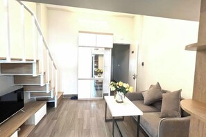 Een moderne woonkamer met een bank, salontafel en een trap die leidt naar een keuken.