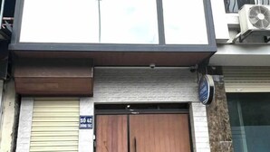 Ein Gebäude mit geschlossenem Rollladen, einem Straßenschild und einer Klimaanlage.