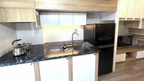 Eine moderne Küche mit schwarzem Arbeitsplatz, einem Edelstahl-Wasserkocher und einer eingebauten Spüle.