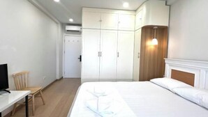 Ein Schlafzimmer mit einem Bett, einem Schreibtisch, einem Stuhl und einem Kleiderschrank.