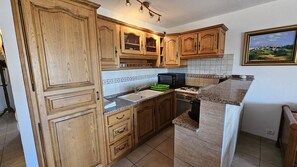 A kitchen with wooden cabinets, a sink, a stove, and a countertop.