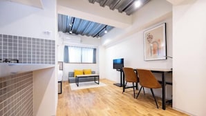 A modern kitchen with a tiled backsplash, a dining area with a table and chairs, and a living space with a sofa and a television. - Gran FusionIkebukuro (Tokyo)